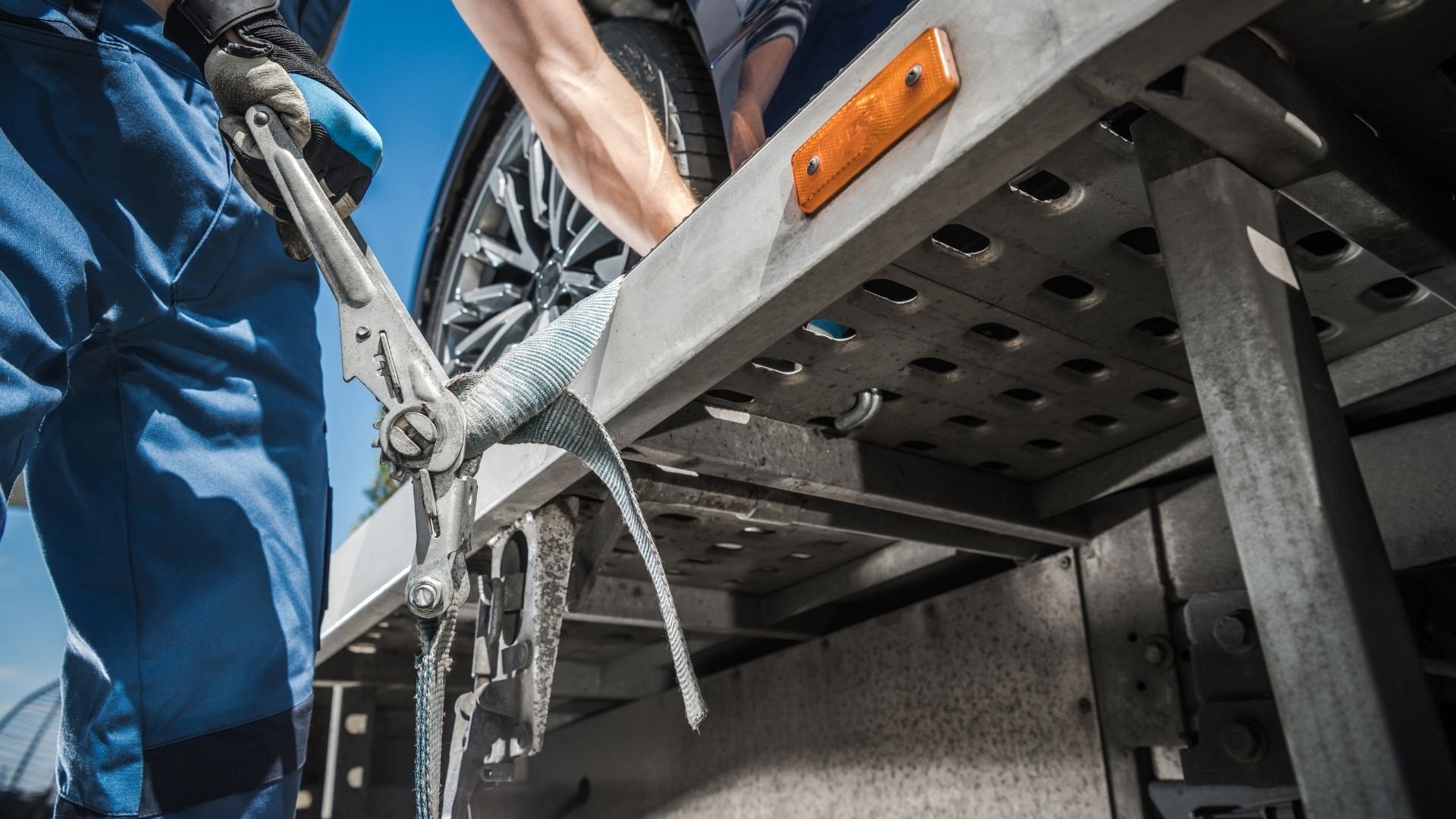 Mechanic securing vehicle with wrench and strap on metal platform