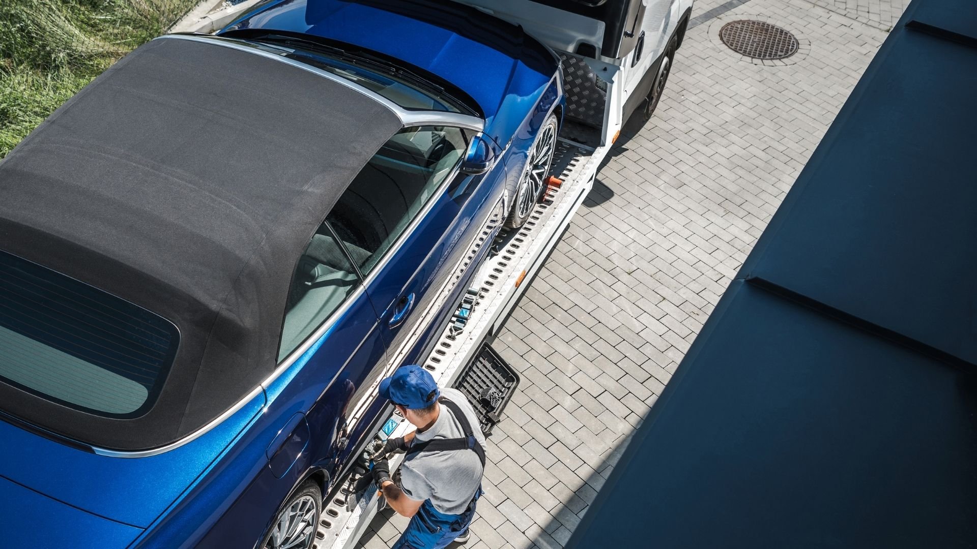 Blue convertible car being loaded onto a transport trailer