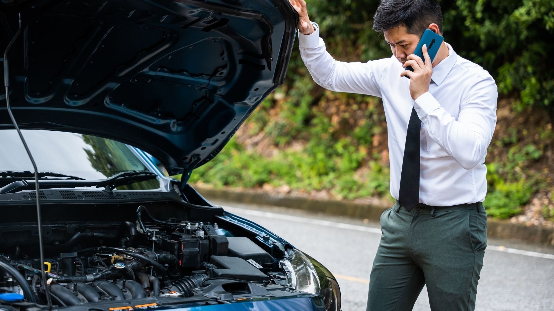 Man in business attire calls for help with broken down car on roadside