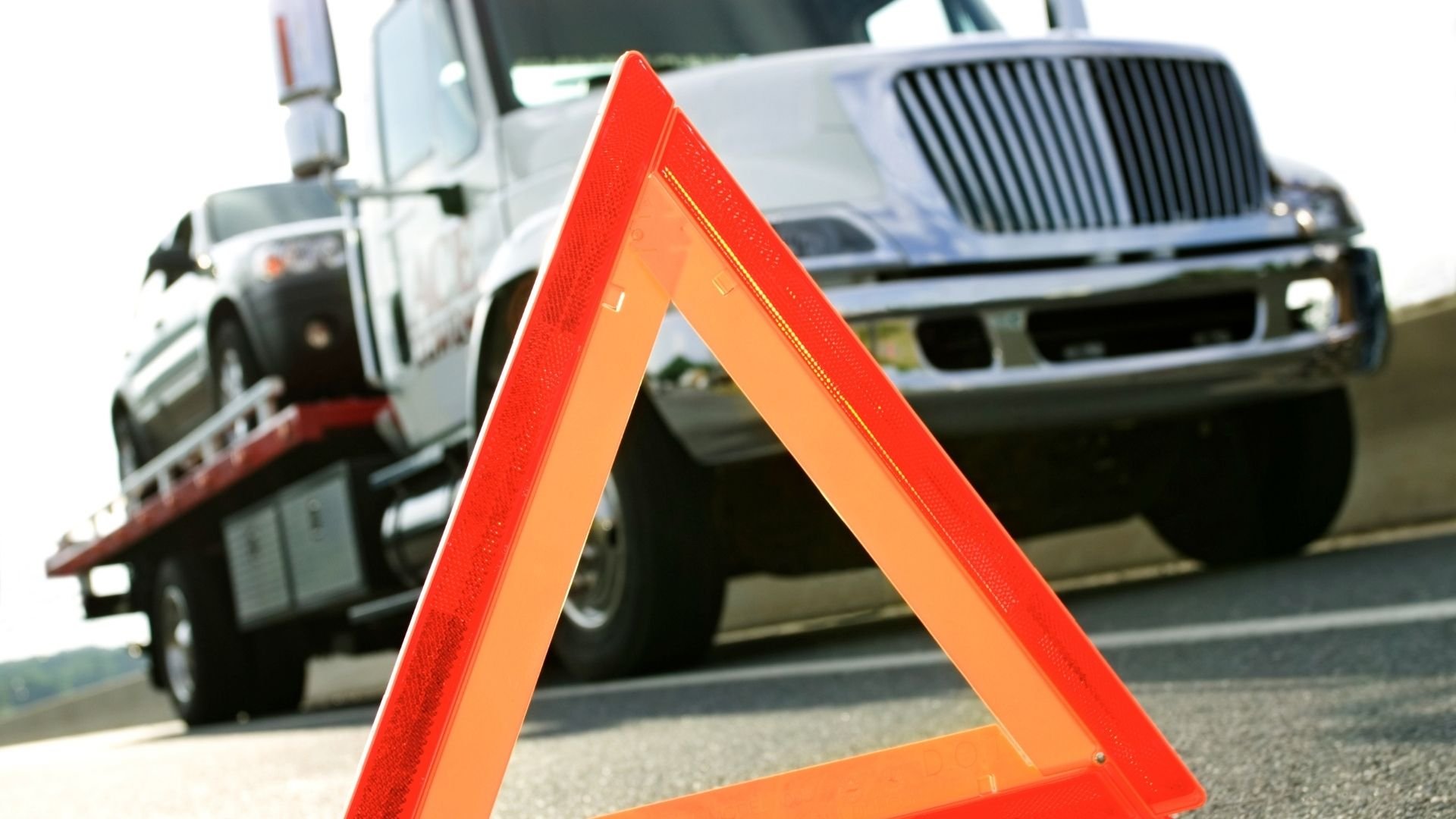 Red warning triangle in front of trucks on roadside indicating vehicle breakdown
